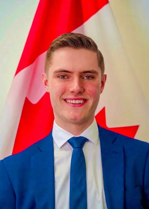 Matt MacFarlane standing in front of the Canadian flag